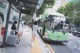 A woman sitting on a bench next to a green bus.