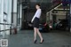 A woman in a white shirt and black skirt standing in a parking garage.