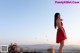 A woman in a red dress standing on a balcony.