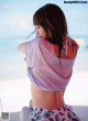 A woman sitting on the beach with her back to the camera.