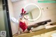 A woman in a red dress sitting on a sink in a bathroom.