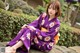 A woman in a purple kimono sitting on a stone ledge.