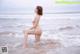 A woman in a white bikini sitting on the beach.