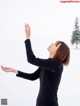 A woman standing in the snow with her arms outstretched.