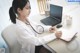 A woman sitting at a desk with a laptop and a stethoscope.