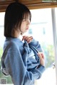 A woman in a blue sweatshirt looking out a window.