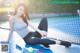 A woman sitting on a tennis court with a racket and ball.