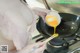 A woman is cooking an egg in a wok with chopsticks.