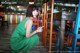 A woman in a green dress sitting on a wooden floor.