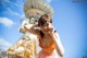 A woman standing in front of a radio tower talking on a cell phone.