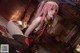 A woman with pink hair sitting on a bed.
