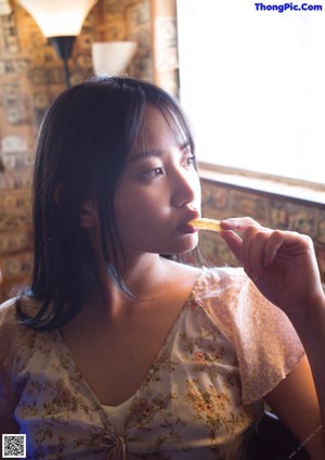 A woman sitting at a table eating a piece of food.