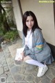 A young woman sitting on the ground holding a book.