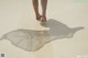 A person walking on a sandy beach with their shadow on the sand.